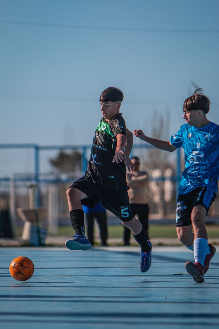 Two boys actively playing soccer outdoors on a sunny day.