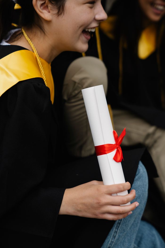 Close-up of a joyful graduate holding a diploma during graduation day.